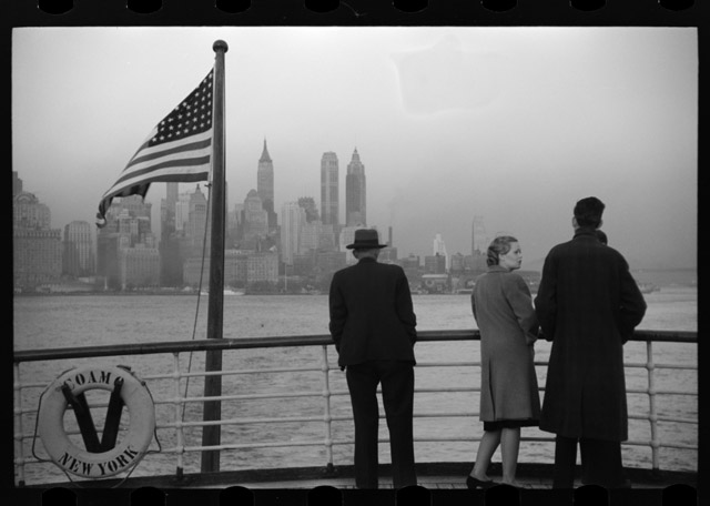 photo of passengers on ship with Lower Manhattan behind